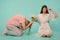 Young man knelt down in the pose of a slave and holding spring flowers, attractive brunette girl in dress twist a finger