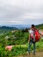 Young man with a large red backpack gazing at Doon Valley from Mussoorie hills, Uttarakhand, India. Serene hilltop views