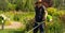 A young man with a lawnmower cares for the grass in the backyard.