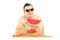 Young man laying on a beach towel and eating a slice of watermelon