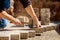 Young man laying gray concrete paving slabs in house courtyard on gravel foundation base. Master lays paving stones