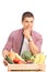 Young man leaning on a crate full of vegetables