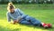 Young man lies on the grass, looks into a smartphone, checks social networks. Concept. Caucasian man relaxing in the