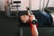 A young man lies on a sports bench lifting dumbbells in the gym during a workout