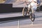 Young man in light clothing slides on the railing on the rear wheel of a BMX bike