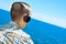 Young man listening to music with headphones in front of the sea