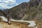 Young man with longboard contemplating a curvy road descending in a valley