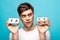 Young man looking away while holding wooden cubes with fake fact lettering isolated on blue