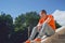 Young man looking away, sitting on stairs of manor. Male tourist posing in sunny weather on stairway of palace.