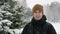 A young man looking at the camera and playing with snow in winter forest. It makes snowballs and throwing them. Winter