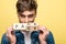 Young man looking at camera while showing wooden cubes with fake fact lettering on yellow background