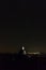 Young man looking to night sky full of stars with distant city, long exposure, Austria landscape