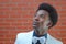 Young man looking up wearing bow tie white jacket brick wall