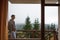A young man looks out from the hotel`s balcony with a view of the mountains, the fog and the fir forest.
