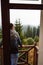 A young man looks out from the hotel`s balcony with a view of the mountains, the fog and the fir forest.