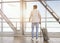 Young man with luggage enjoying window view at airport