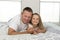 Young man lying on bed together with adorable 7 years old little girl playing happy at home in family father and daughter love li