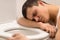 Young man lying on toilet seat.