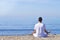 Young man makes meditation in lotus pose on sea / ocean beach, harmony and contemplation. Boy practicing yoga at sea resort at her