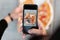Young man makes a photo of delicious pizza on a smartphone. Closeup of male hands and pizza image on screen.  Top view.