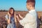 A young man makes proposal his girlfriend. Summer bright sunny day in wheat field. In hands holds box with gold ring