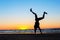 Young man making handstand on the beach. Multicolored sunset background