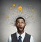 Young man with many idea light bulbs above head looking up