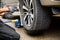 Young man mechanic wearing gloves,car repair,changing tire using wrench to fix car wheel flat tire on the road,transportation and