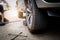 Young man mechanic wearing gloves,lifting the car on the jack for car repair in outdoor,changing flat tire with wrench on the road