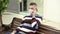 A young man in a medical mask sits on a bench in a shopping center and talks on the phone. The masked man protects