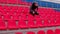 Young man in medical mask sitting on stadium bleachers alone. Sad adult male protecting yourself from diseases at sports