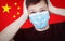 Young man in a medical mask is very scared on the background of the Chinese flag