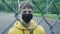 Young man in a medical protective mask behind a metal mesh fence