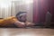 Young man meditating on a floor and lying in Makarasana pose at his living room