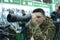 Young man in military uniform looking through portable monocular telescope, gun shop