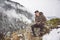 Young man at mountain sitting under snow