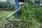 Young man mowing the grown grass with a scythe