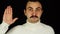 Young man with mustache is pledging allegiance with his right hand raised over black background