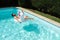 Young man naked on a big unicorn inflatable ring in a swimming pool