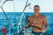 Young man with naked body at the helm of a sailing yacht boat. Sport.