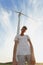 Young man next to electric wind turbine. A guy on a windmill farm background. Alternative sources concept. Copy space.