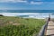 Young man observing waves on wooden pathway on beautiful atlantic coast