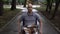A young man with oncology rides a wheelchair through the park. The man is bald due to chemotherapy.
