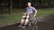 A young man with oncology rides a wheelchair through the park. The man is bald due to chemotherapy.