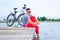 Young man, one happy tourist bicyclist map wearing in gray shirt with glasses sitting at the beach and resting after bicycle ride