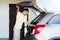 Young man with open car trunk at parking space