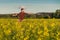 Young man with opened arms wide in rape field feeling freedom