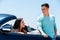 Young man opening car door to woman.