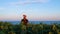 Young man in orange cap in yellow sunflowers crops field on sunset sea shore. Male tourist with backpack on countryside