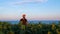 Young man in orange cap in yellow sunflowers crops field on sunset sea shore. Male tourist with backpack on countryside